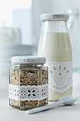 Milk and muesli for breakfast on the go in screw-top jars decorated with lace ribbon
