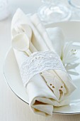 Napkin ring made from lace trim around ornate cutlery & linen napkin on plate