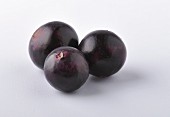 Three acai berries against a white background (close-up)