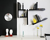 Sideboard against black and white wall with small shelves arranged asymmetrically