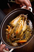 Guinea fowl stuffed under the skin, cooked with peas, carrots and olives