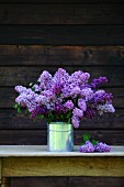 A bouquet of purple lilac in a milk can