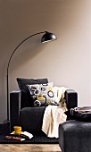 Arc lamp next to black armchair with scatter cushions