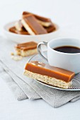 Shortbread topped with caramel, with a cup of coffee