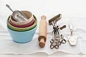 Baking utensils: bowls, a rolling pin, a rotary whisk and a cake slice