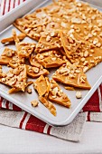A slab of toffee with cashew nuts on a baking tray