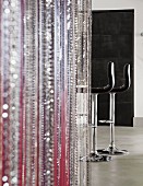 Bead curtain in various colours; black leather bar stools in background