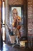 Hats and bags on vintage, metal coat stand against exposed brick walls in niche in hallway
