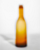 An out-of-focus orange bottle with cork on a white background
