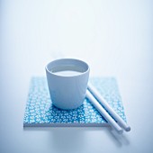 Sake in a cup next to a pair of chopsticks