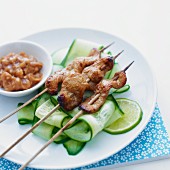 Skewers of chicken, served with cucumber slices and a satay side-dish