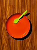 Red plate, with green wooden spoon on a wood effect background