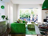 Green accents in open-plan living area with view of young family on terrace