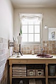 Rustic washstand with sink against tiled wall below lattice window in country-style ambiance