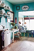 Türkisblau gestrichene Vintage-Küche mit Tagesbett in Fensternische und maritimer Wanddeko