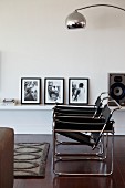Two Wassily chairs in interior in front of black and white photos on low, floating shelf