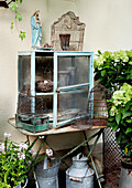 Vintage garden decoration with old cupboard, bird cages and hydrangeas