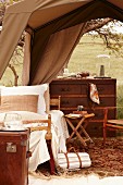 Elegant sleeping area with colonial-style chest of drawers below tent roof and view of landscape