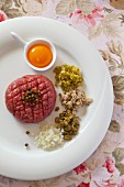 Steak tartare with egg yolk, capers, onions, mushrooms, pickled vegetables and green peppercorns