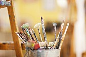 Different paintbrushes in container next to easel (close-up)