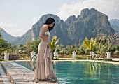Frau tippt Fuss in Wasser eines Swimmingpools (Vang Vieng, Laos)