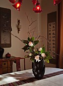 Oriental-style living area with Chinese wall hangings and flower arrangement in black lacquer vase