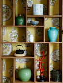 Small ornaments in backless display case against wallpaper with crockery motif