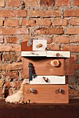 Stacked boxes with furniture handles attached to fronts against rustic brick wall