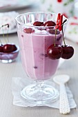 A glass of cherry yogurt garnished with fresh cherries
