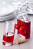 Cherry liqueur in a small bottle decorated with a fake cherry, some poured into a glass