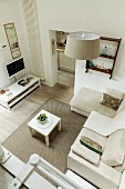 View down into lounge area with pale upholstered furniture on rug and wooden floor in modern setting