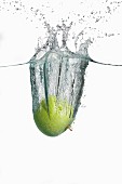 A green apple falling into water