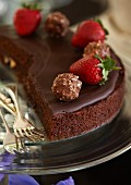A fine chocolate cake made with cranberries and chocolate ganache and decorated with strawberries and nut pralines