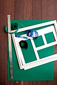 Green construction paper, white picture frame, photo mount, metal ruler and velcro tape on wooden surface