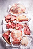 Assorted cuts of meat and a chicken breast on paper