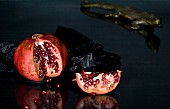 pomegranate with slice removed on a black glass table