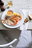 Garlic prawns with dip, chunks of bread, and beer on a table