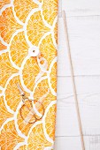 Length of fabric with yellow and orange pattern, scissors and wooden rod