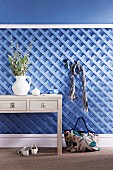 Holzspalier hellblau gestrichen als Garderobe nutzbar, davor ein Schubladentisch mit Dekoration