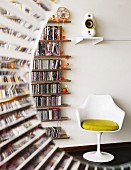 Halbrunder Durchblick auf einen weissen Tulip Chair von Eero Saarinen neben schmalem Wandregal mit umfangreicher CD-Sammlung