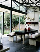 Rustic dining table and matching benches below custom-built pendant lamp in hall-type interior with open terrace doors