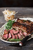 Whole and Sliced New York Strip Steaks on a Platter with Rosemary