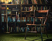 Old wooden chair & standard lamp in front of bookcase