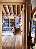 View through open door into rustic bedroom with wooden floor