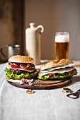 A beefburger and a herring sandwich on a wooden board
