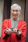A Japanese man holding bonito and bonito flakes