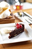 A slice of chocolate and almond torte with raspberries