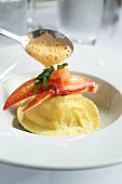 Lobster ravioli being drizzled with sauce