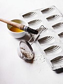 A baking tin for madeleines, flour, egg yolk and a pastry brush