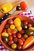 Cherry tomatoes and peppers in a bowl and on a chopping board